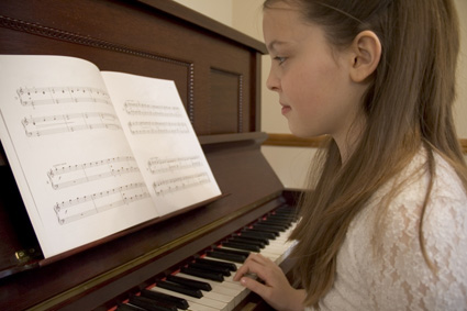 Girl doing <b>her piano</b> practice at an upright <b>piano</b> - piano-practice-girl